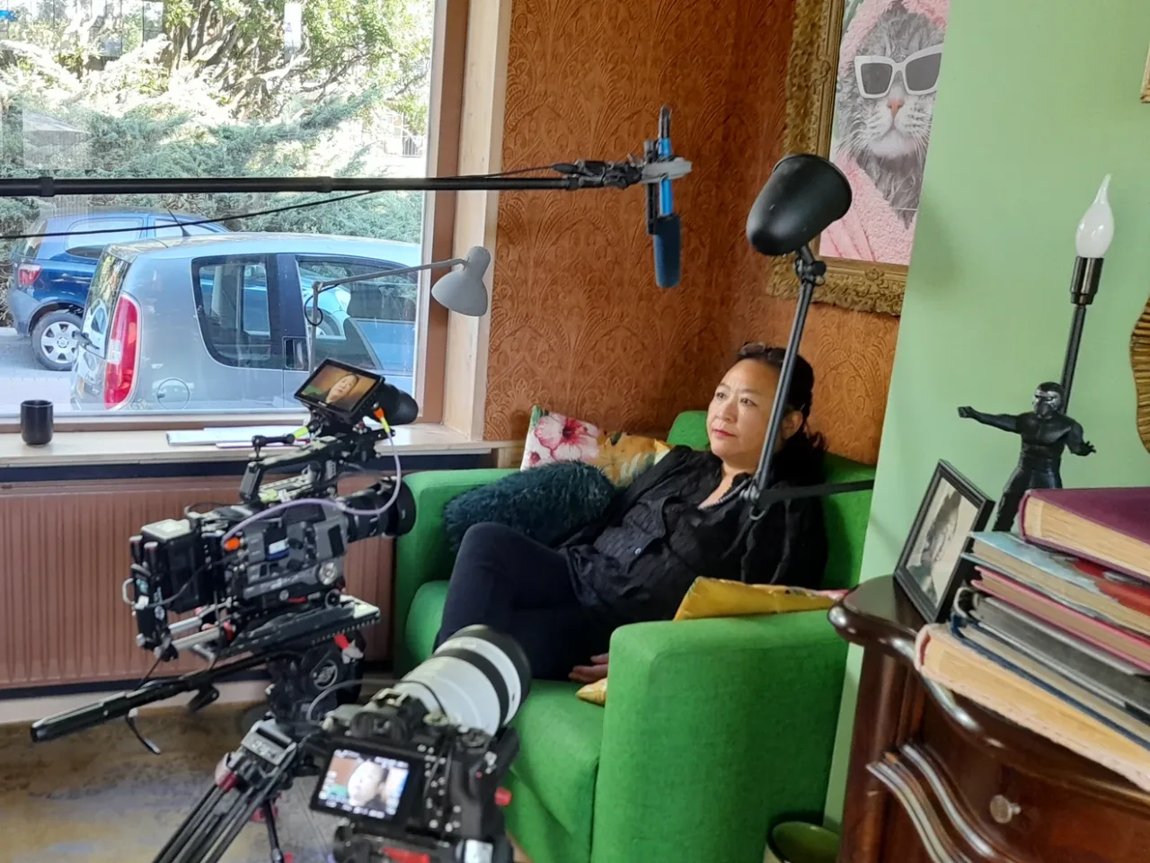 Opstelling voor een gefilmd interview in een woonkamer, met een geïnterviewde, camera's en microfoons.