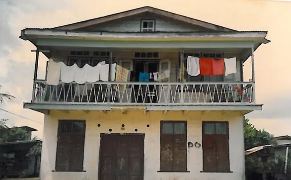 Een familiehuis met een veranda en wasgoed aan de balustrade.