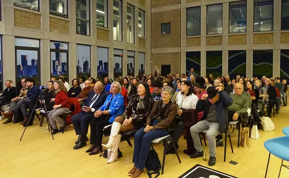 Bezoekers zitten samen in een volle zaal tijdens een bijeenkomst.